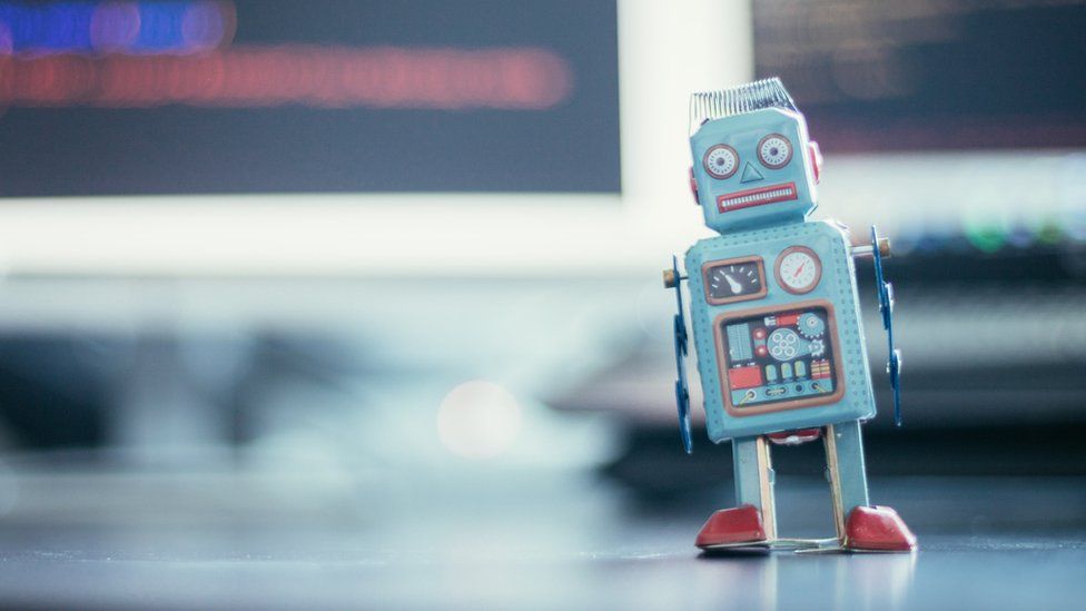 A stock image of a robot in front of computer screens