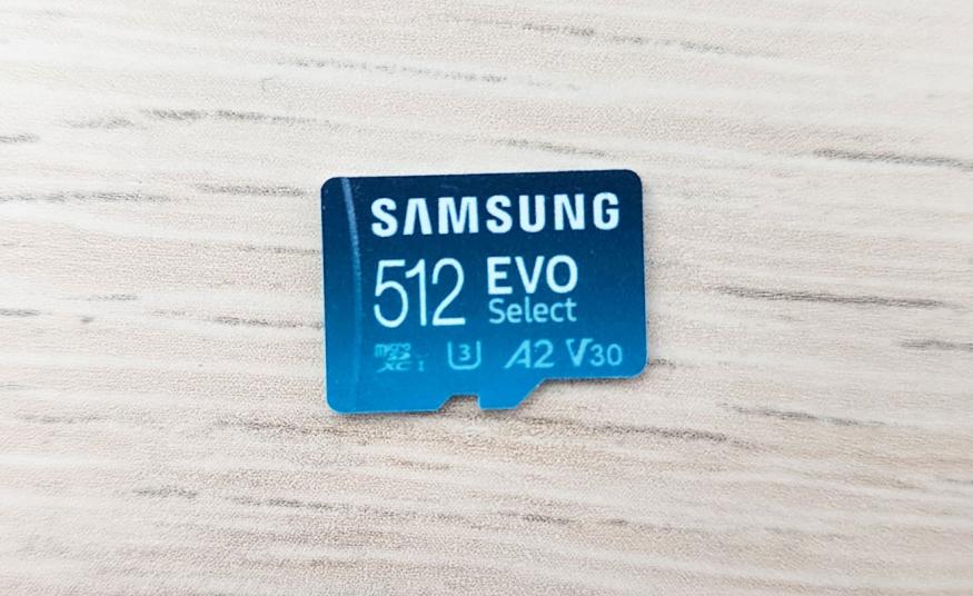 A closeup of a Samsung 512 EVO Select microSD card on a white wood-textured tabletop.