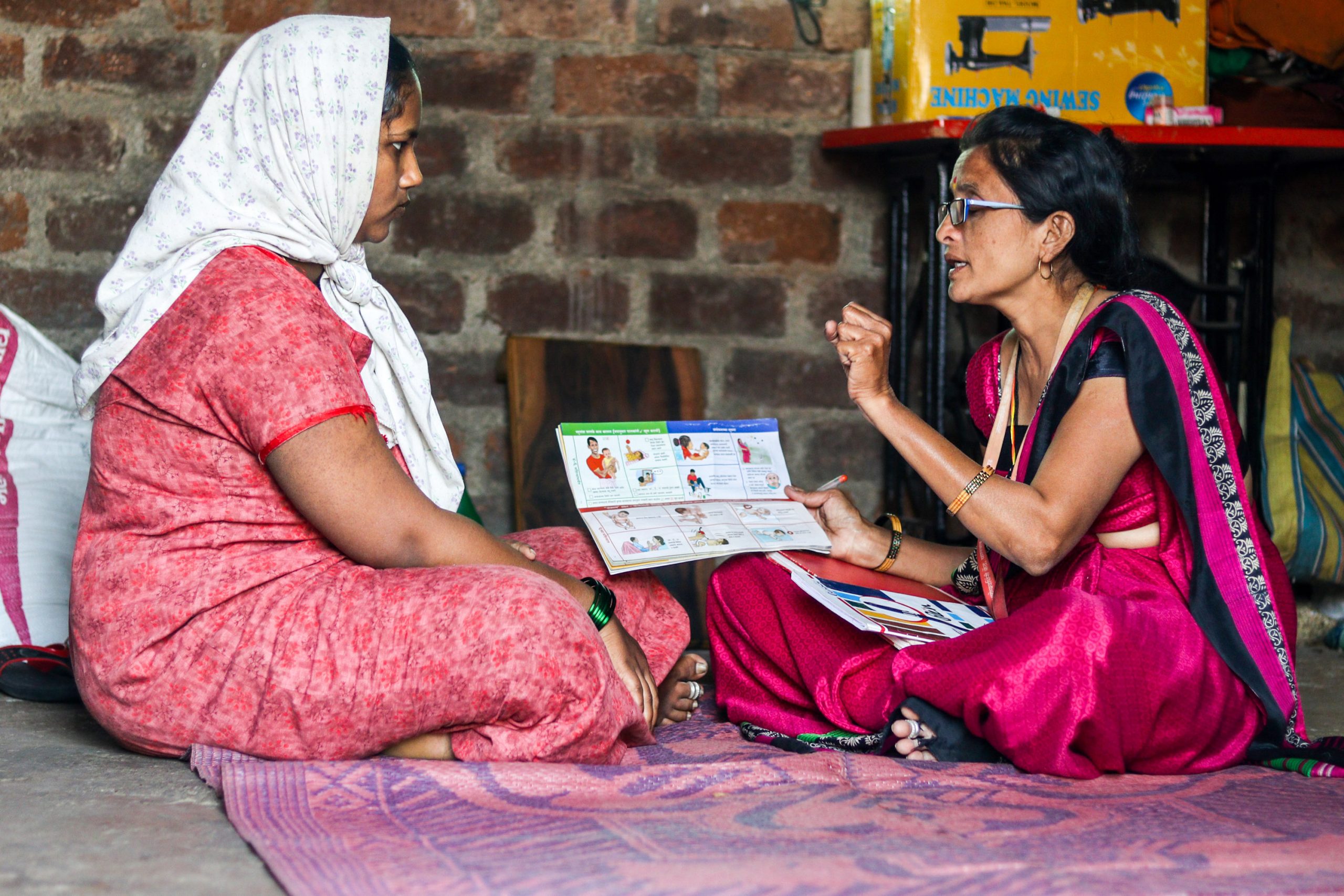 Maya Patil sits speaking with one-on-one with an expectant mother