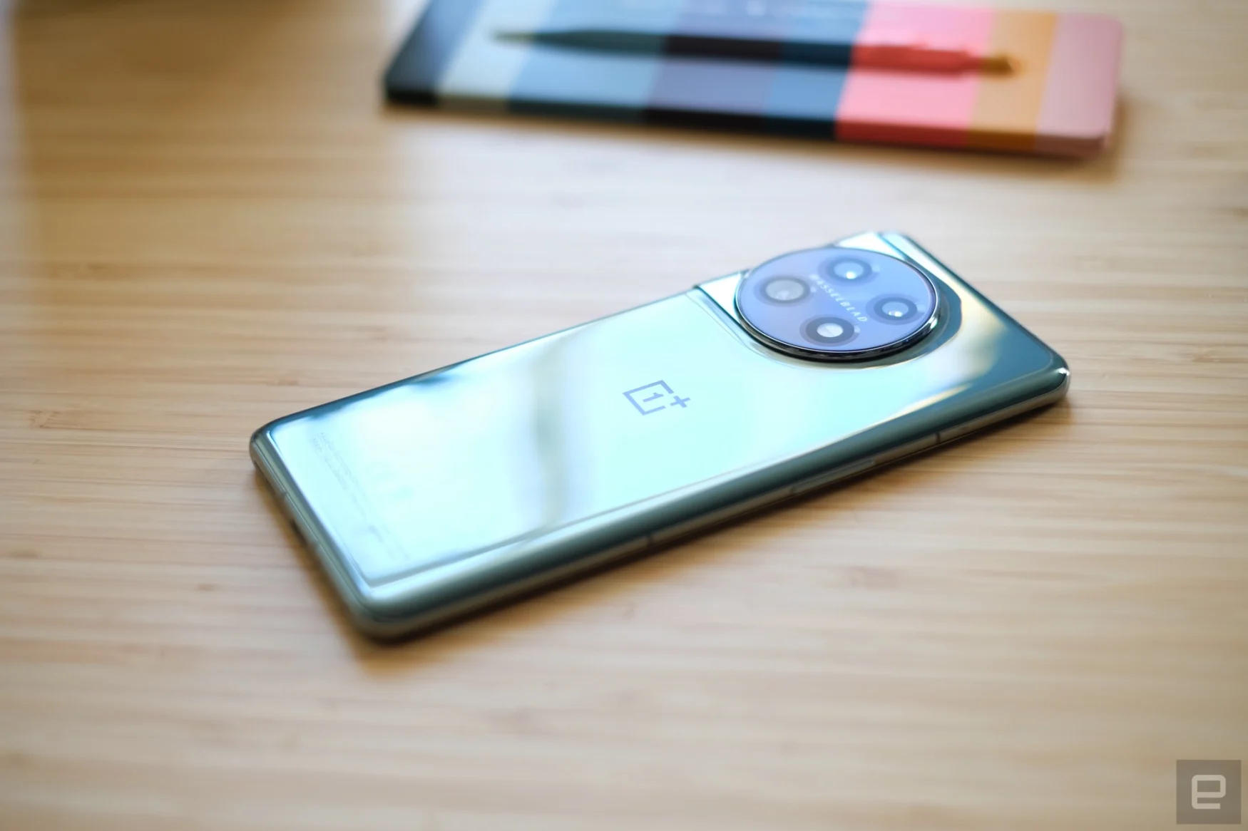 OnePlus 11 smartphone lying on a bamboo table.