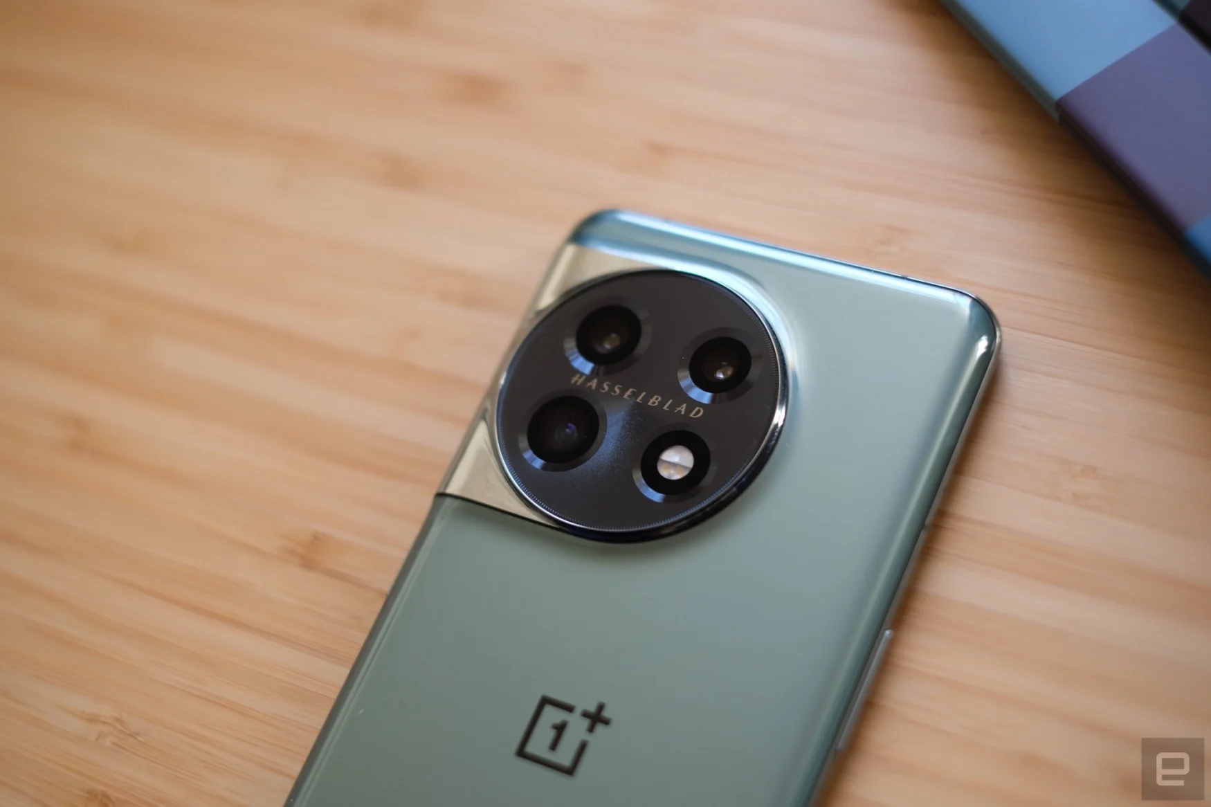 OnePlus 11 smartphone lying on a bamboo table.