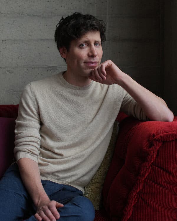 Sam Altman, sitting on a red couch, at the OpenAI offices.