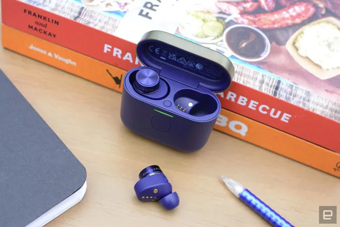 Image of a pair of new Bowers and Wilkins earbuds propped up against some barbecue recipe books. 