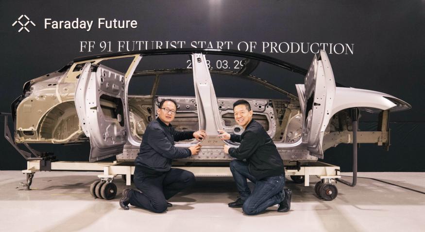 A photo of the Faraday Future FF91 Futurist electric vehicle frame with two of the FF team kneeling in front of it.