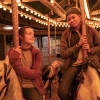 Bella Ramsey & Storm Reid smiling at each other while riding a carousel at night