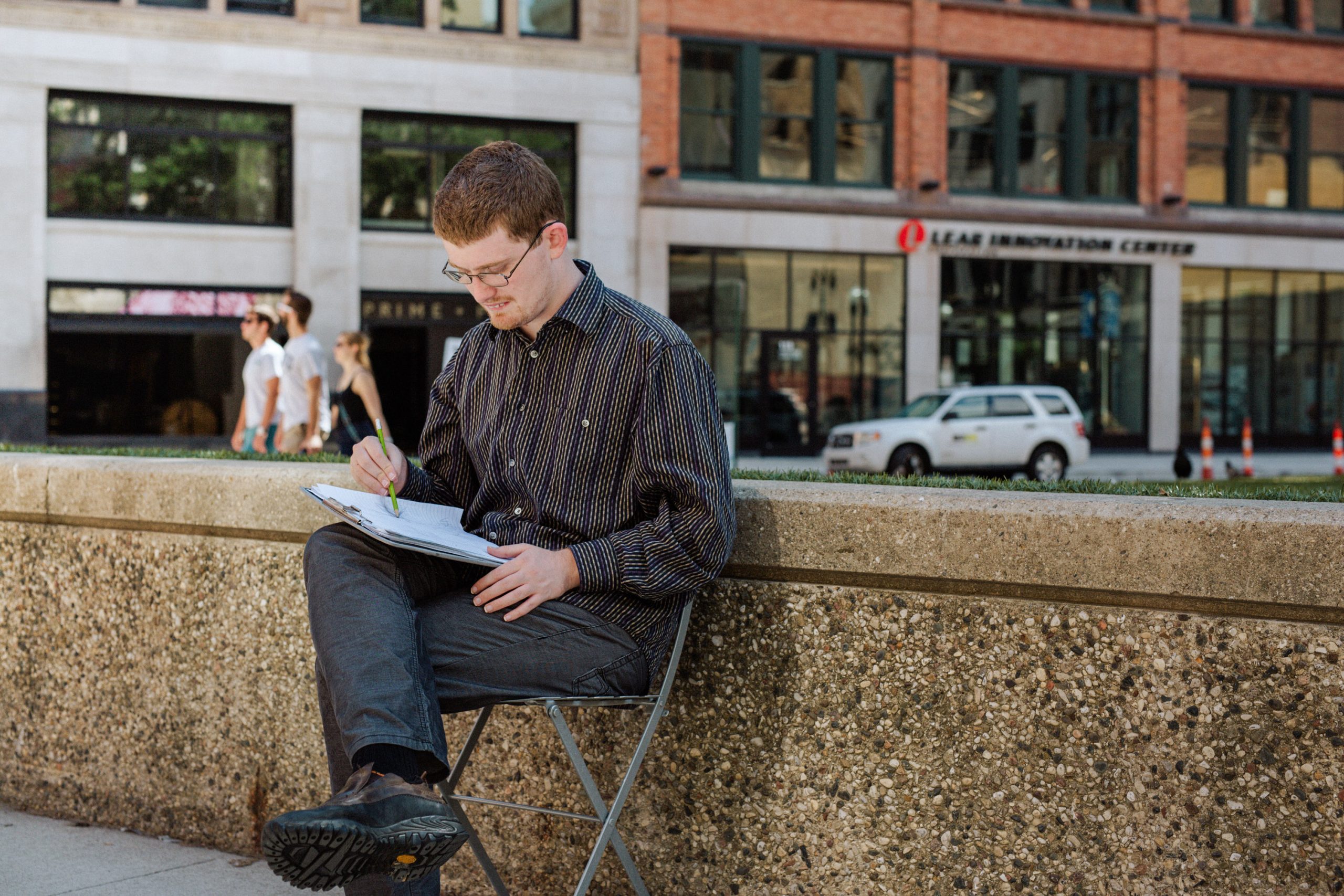 DJ Savarese sits outdoors, holding a clipboard and pencil in his lap