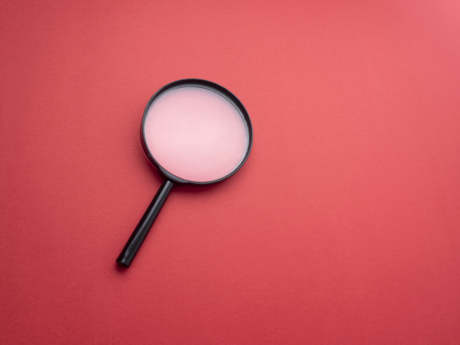 Magnifying glass on red colored background.