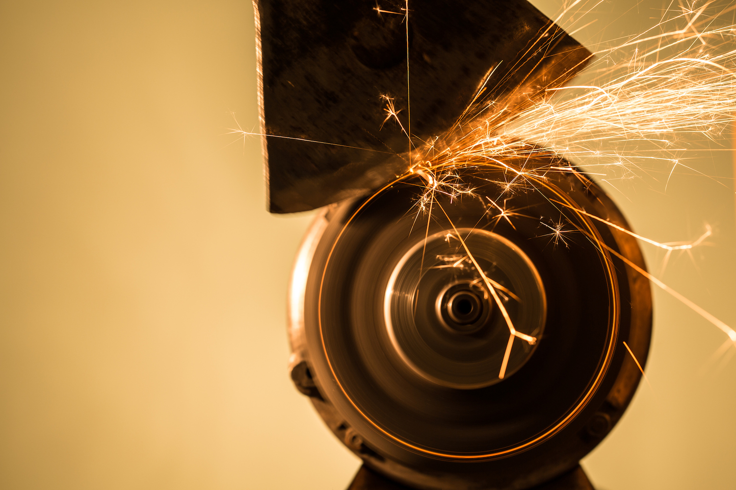 Close-up of an axe against a sharpening wheel throwing off sparks