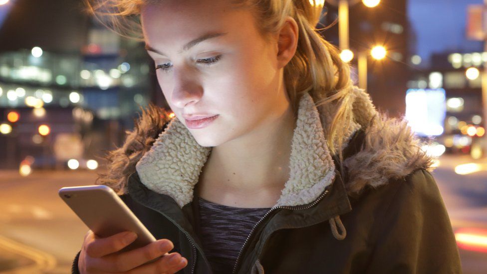 A stock photo of a young woman looking at a phone