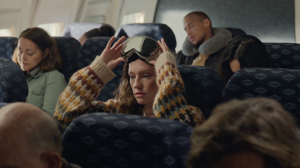 Woman on a plan with Apple's Vision Pro on top of her head 