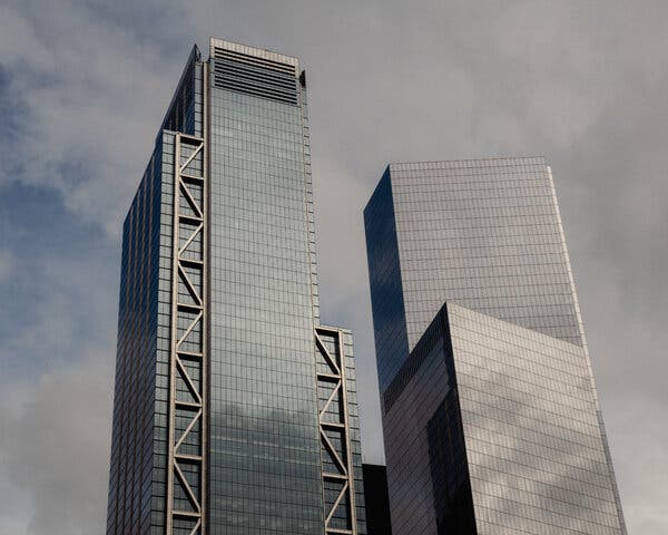 Two office buildings at the World Trade Center site in Downtown Manhattan. The sky in the background is overcast and dark.