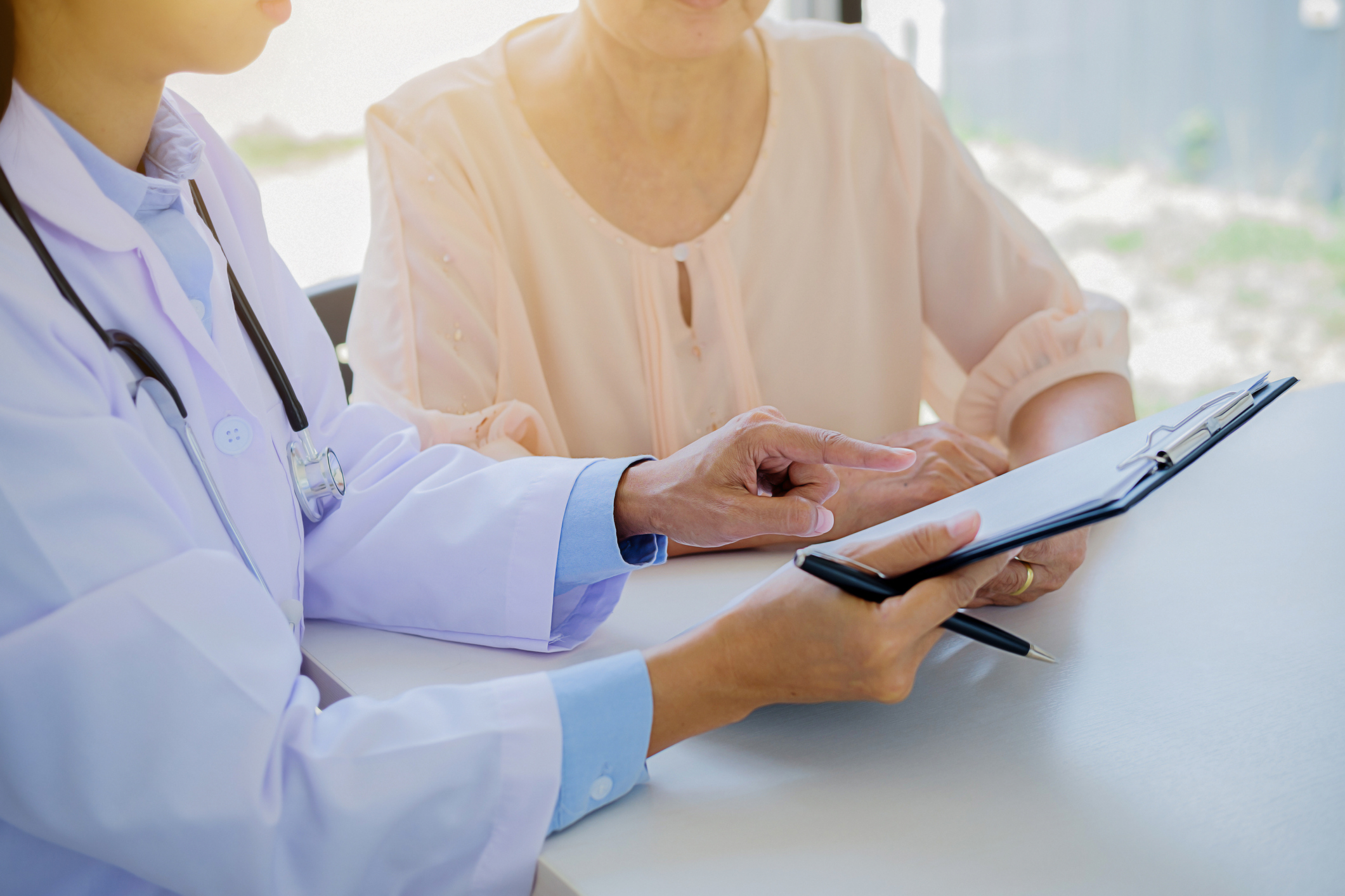 Female Doctor Showing Clipboard To Patient In Hospital
