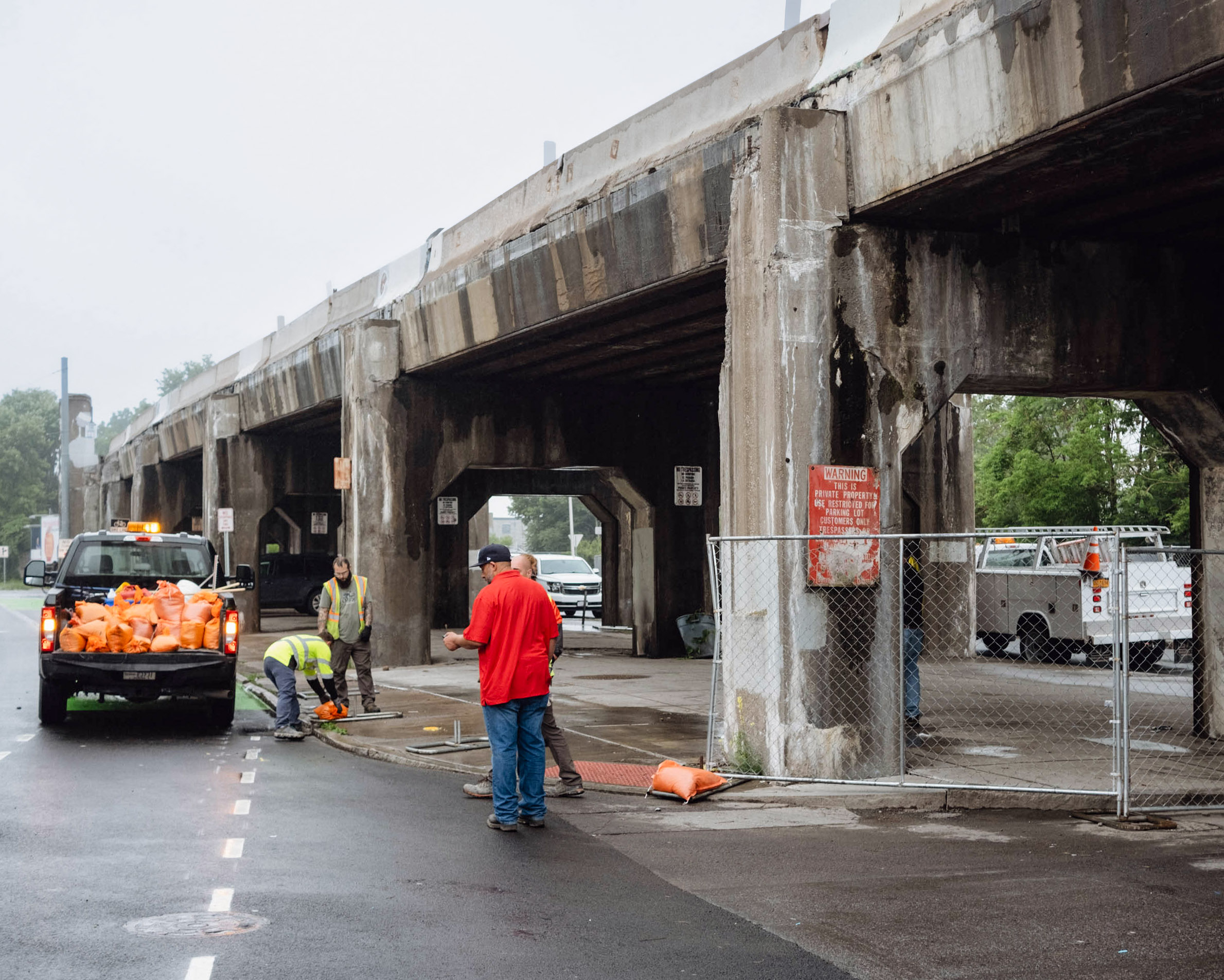 City of Syracuse employees fence in areas alongside an overpass.