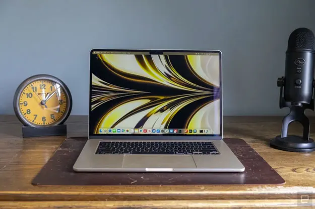 Image of a MacBook Pro on a wooden desk next to an old-timey alarm clock and a Blue Yeti microphone.