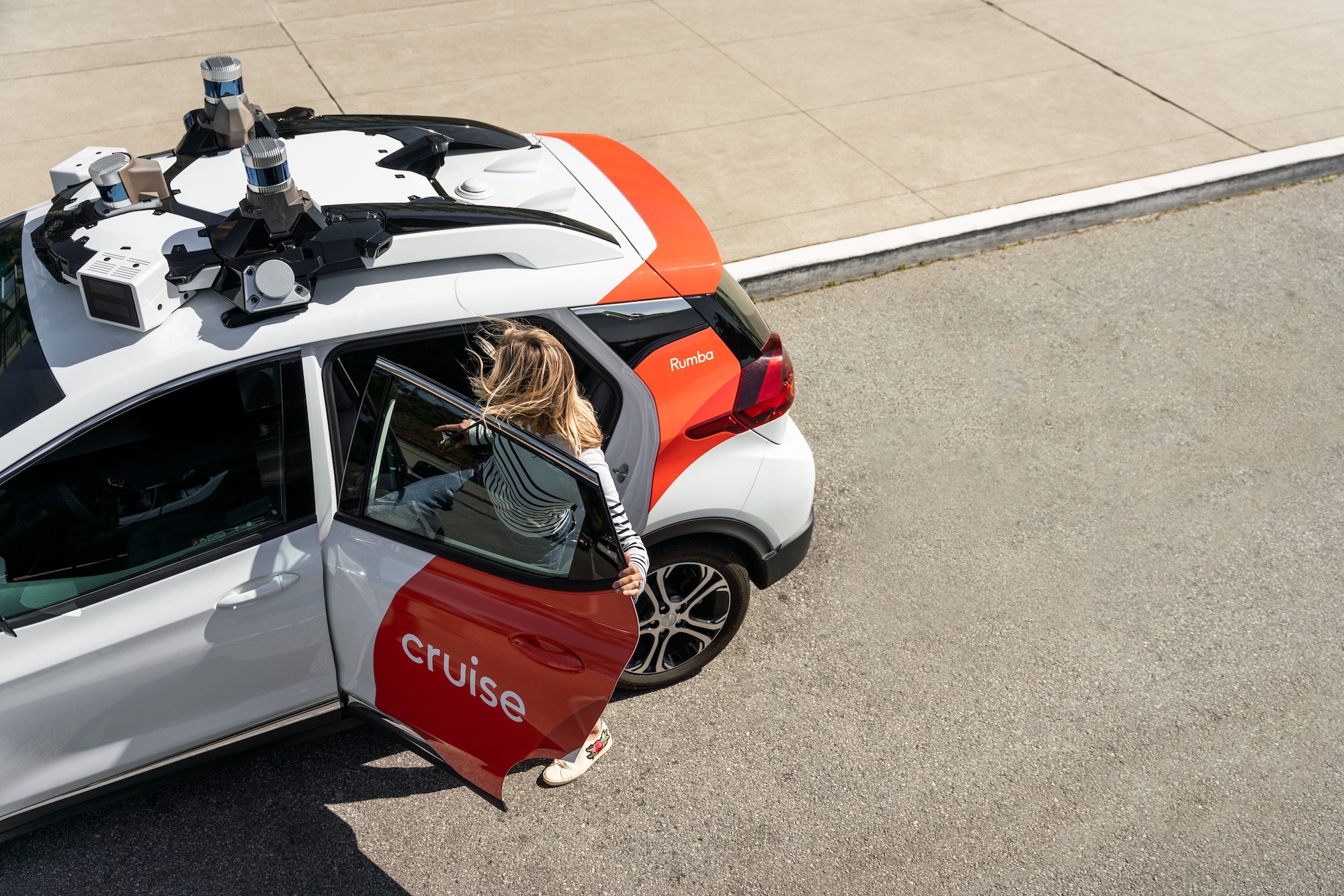 A person getting into the back seat of a driverless Chevy Bolt operated by Cruise.