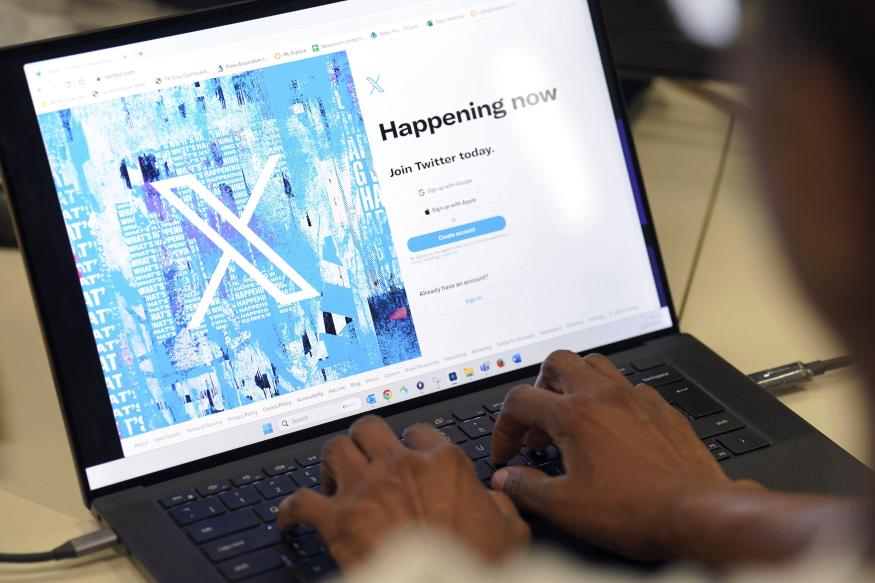 Una persona posa para una foto mientras se registra en Twitter, en una pantalla que muestra el nuevo logotipo de la plataforma, en una oficina en el centro de Londres, el lunes 24 de julio de 2023. (Jonathan Brady/PA via AP)