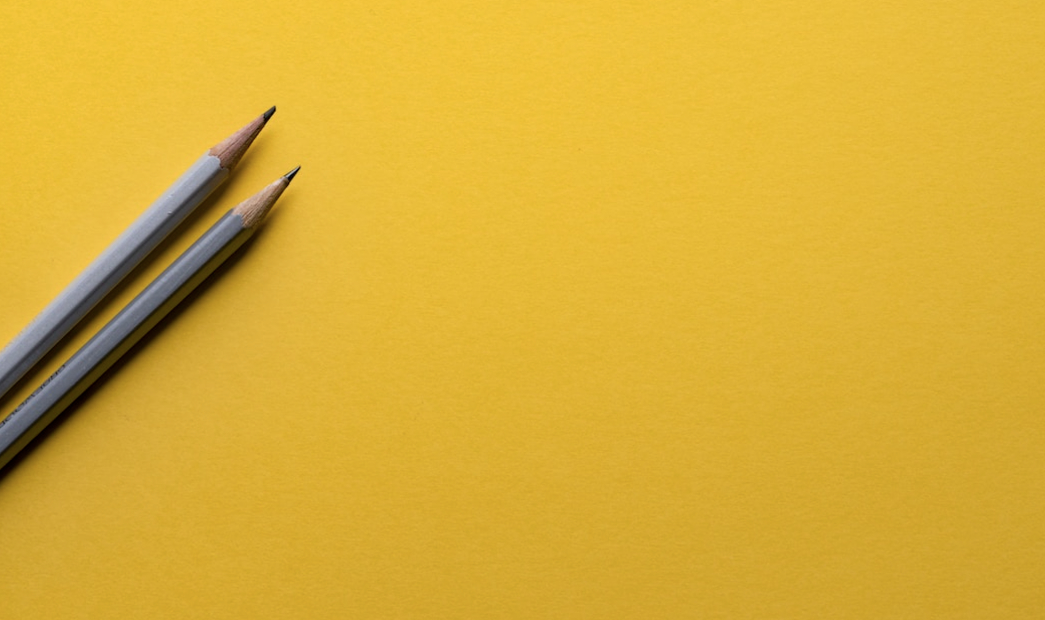 Two gray pencils against a yellow background to represent the start of creating a treemap chart