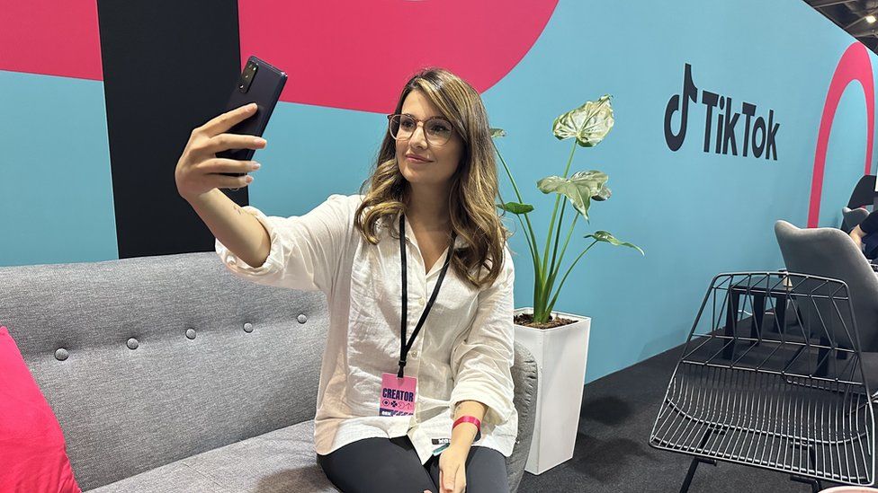 A woman holds a phone while sitting on a sofa