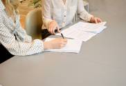 Businesswomen discussing merger and acquisition with paperwork