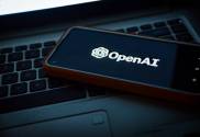 An image of a phone placed on a laptop. The phone has the OpenAI logo on screen. The company behind ChatGPT have entered into a deal with Axel Springer