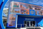 A representation of how Walmart's new AI may look. A women is walking into a Walmart store and all around the entrance are screens showing people using different Walmart products.