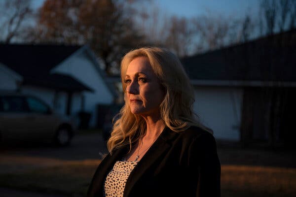 Christine Dowdall standing on the street outside her home as night falls. 