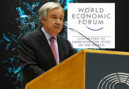 UN chief Guterres warns of 'unintended consequences' of AI. Antonio Guterres speaks behind wooden podium with World Economic Forum sign behind and AI futuristic image as background.