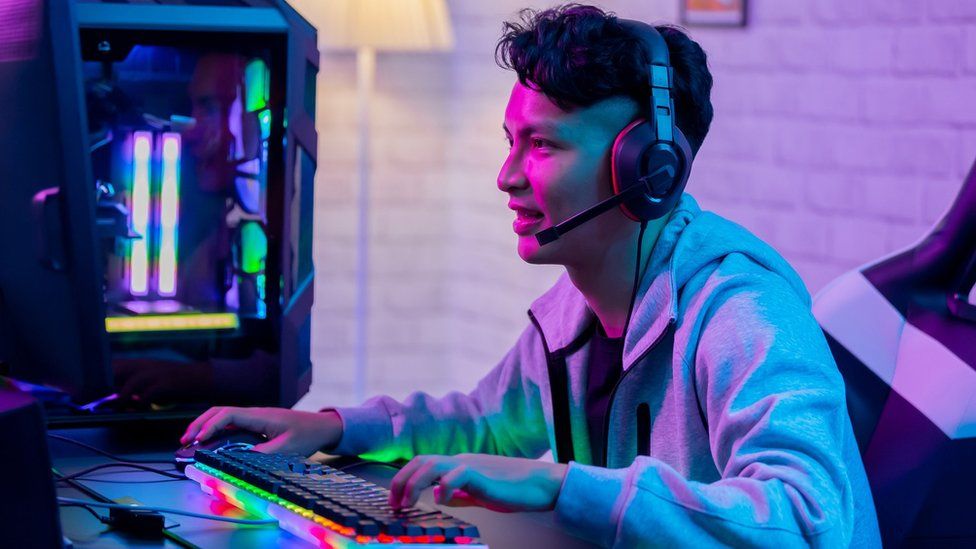 An Asian man playing a game on a desktop computer