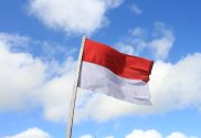 Photo of the Indonesian flag waving in front of a blue, cloudy sky